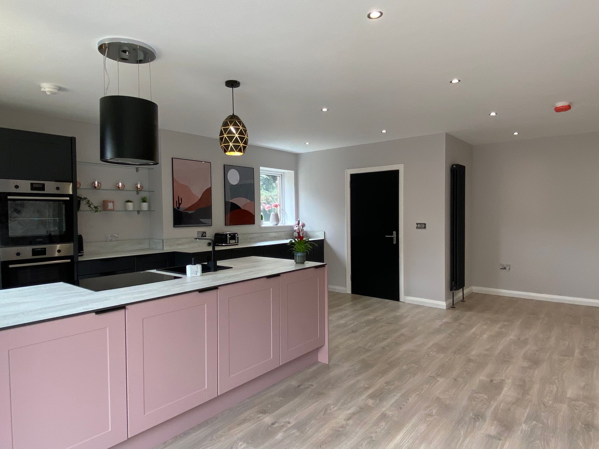 A kitchen with pink cabinets and a black door.