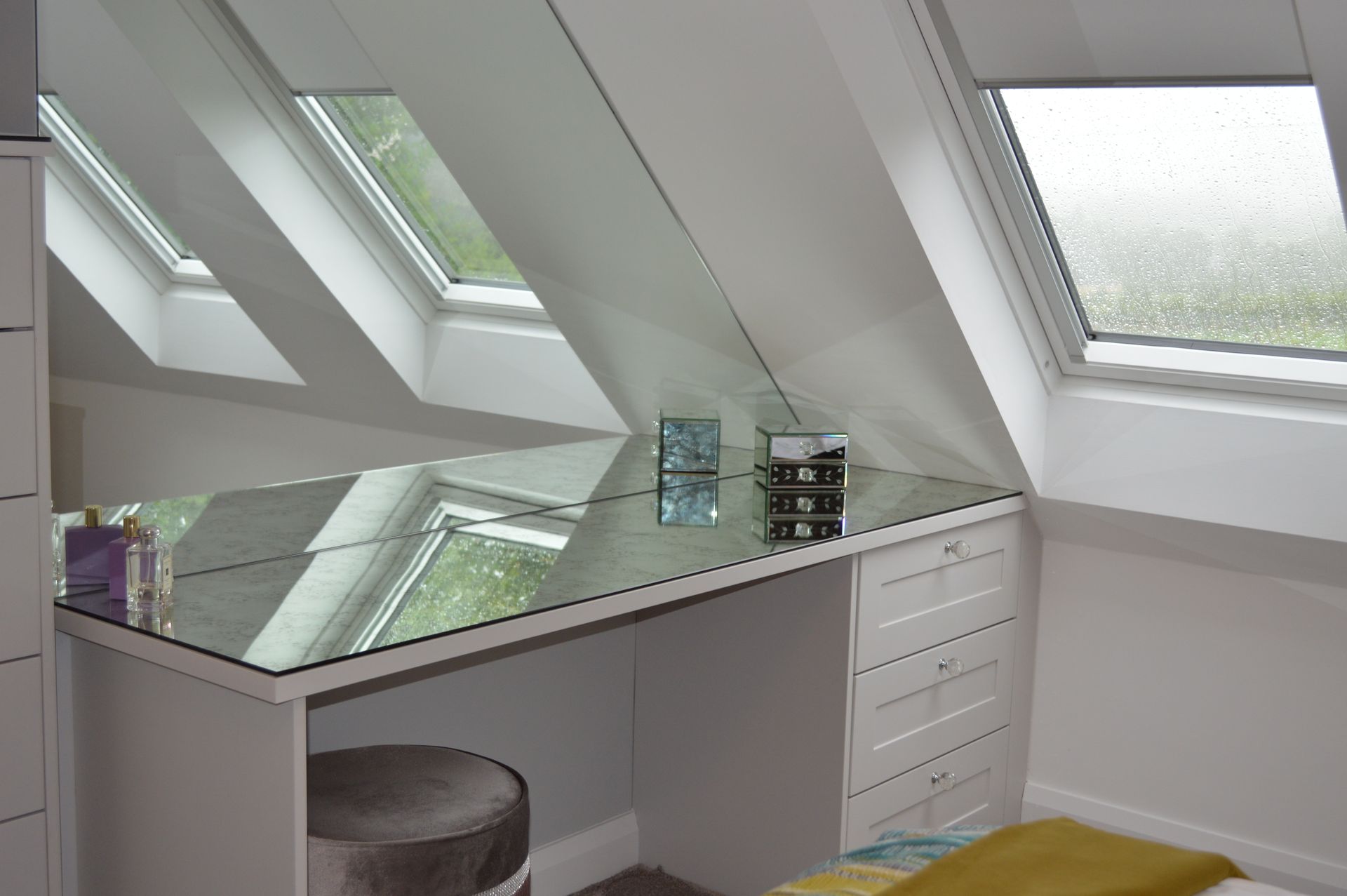 A bedroom with a mirrored desk and a window