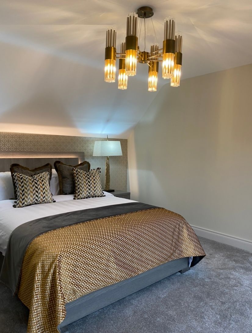 A bedroom with a large bed and a chandelier hanging from the ceiling.