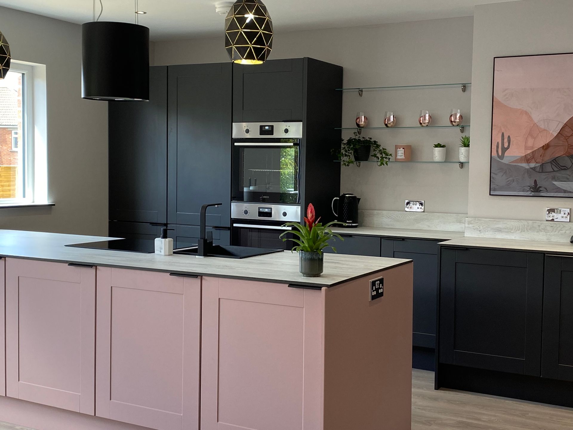 A kitchen with pink cabinets , black cabinets , and a large island.