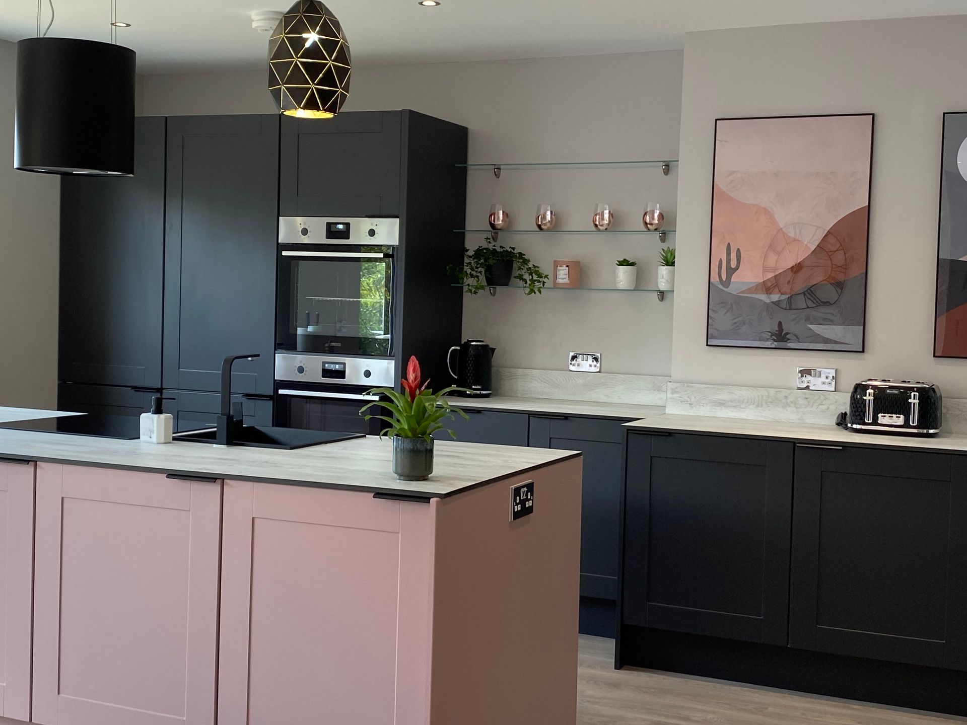 A kitchen with black cabinets and a pink island