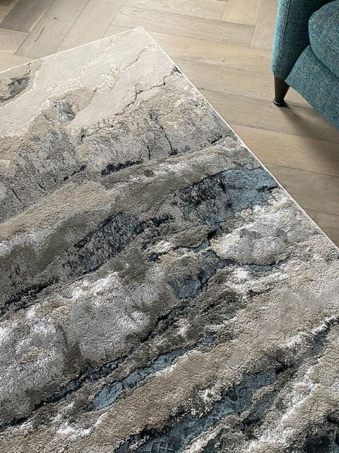 A rug is sitting on a wooden floor next to a chair.