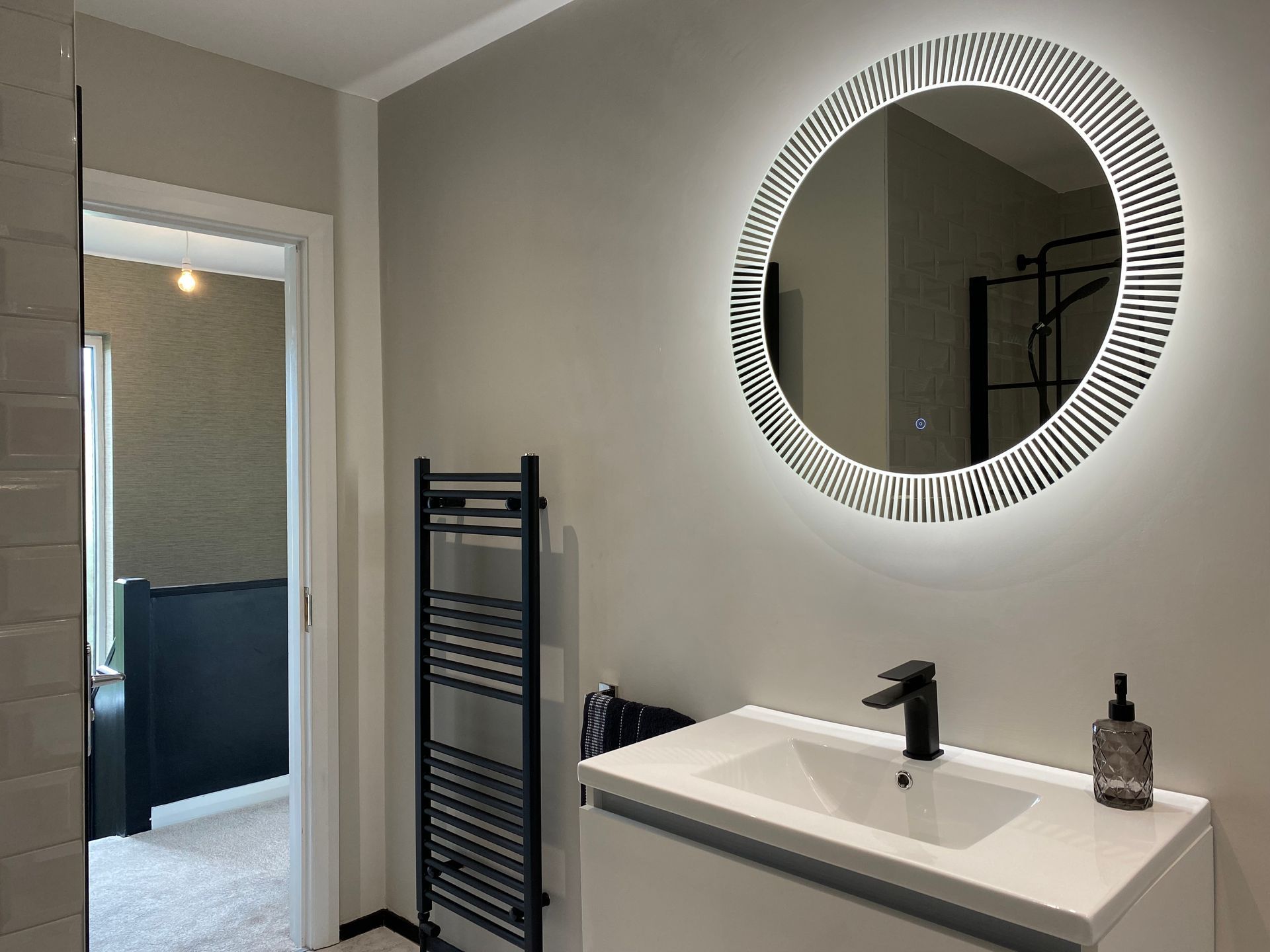A bathroom with a sink , mirror and towel rack.