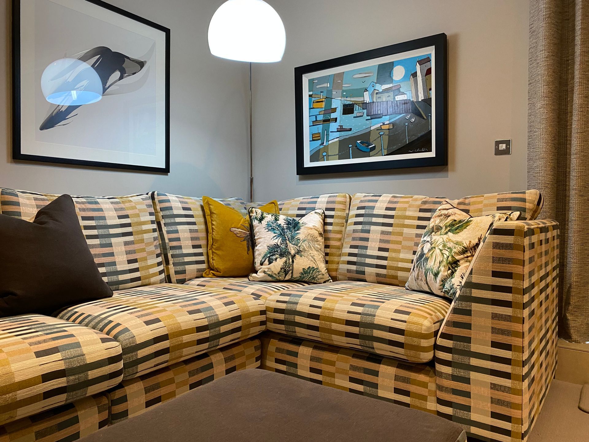 A living room with a sectional couch and two paintings on the wall.