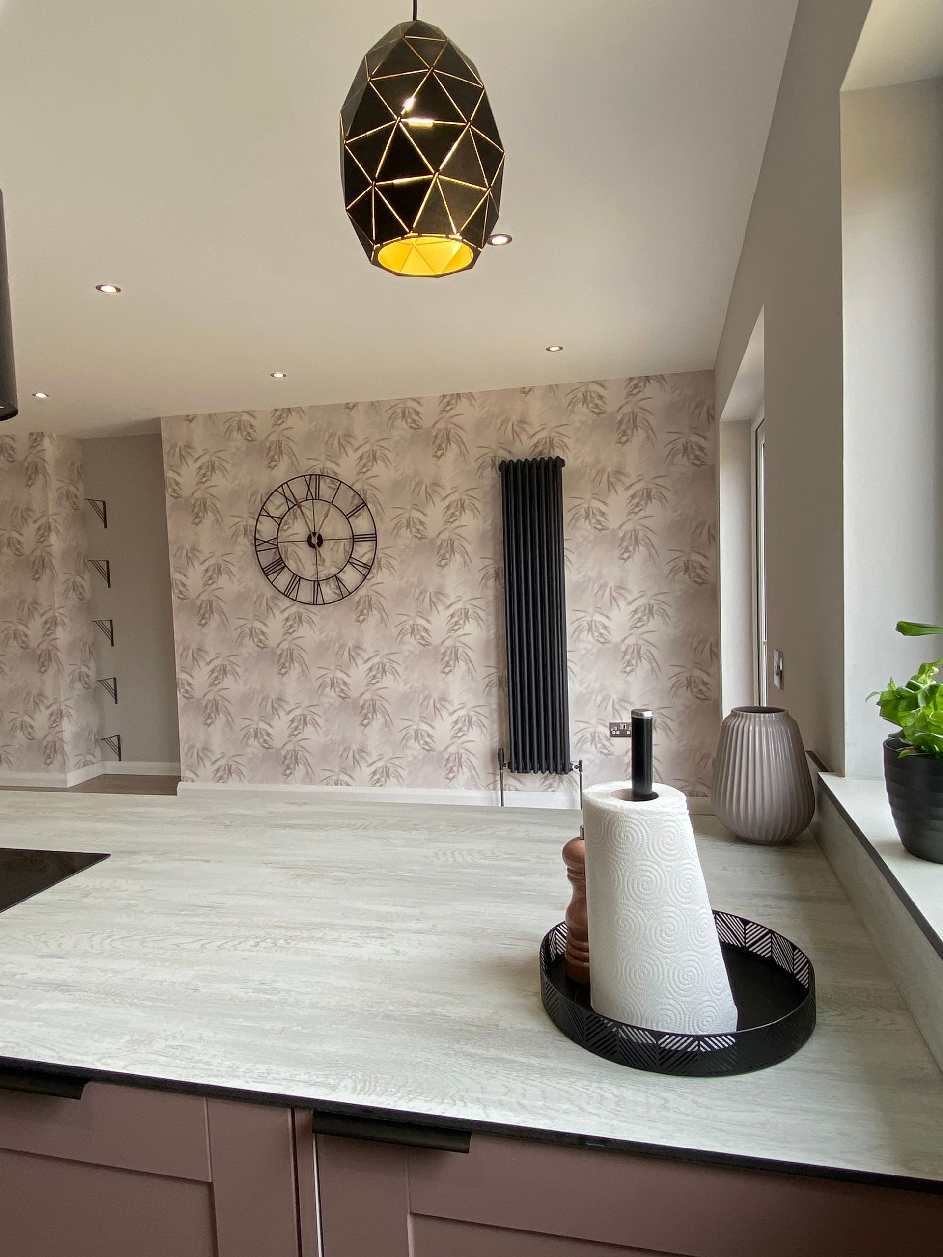 A kitchen counter with a paper towel holder and a clock on the wall.