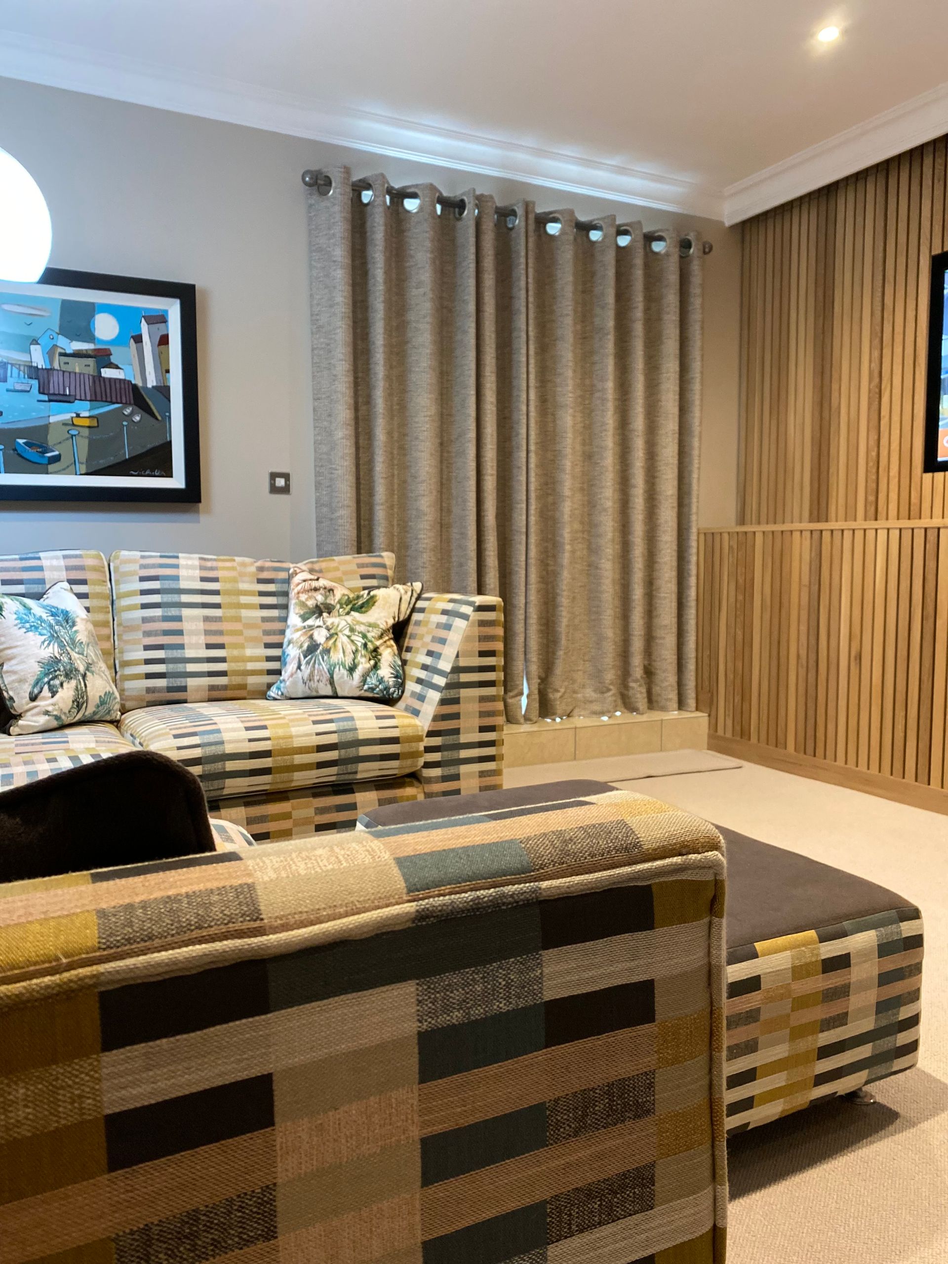A living room with a couch , chair , ottoman and television.