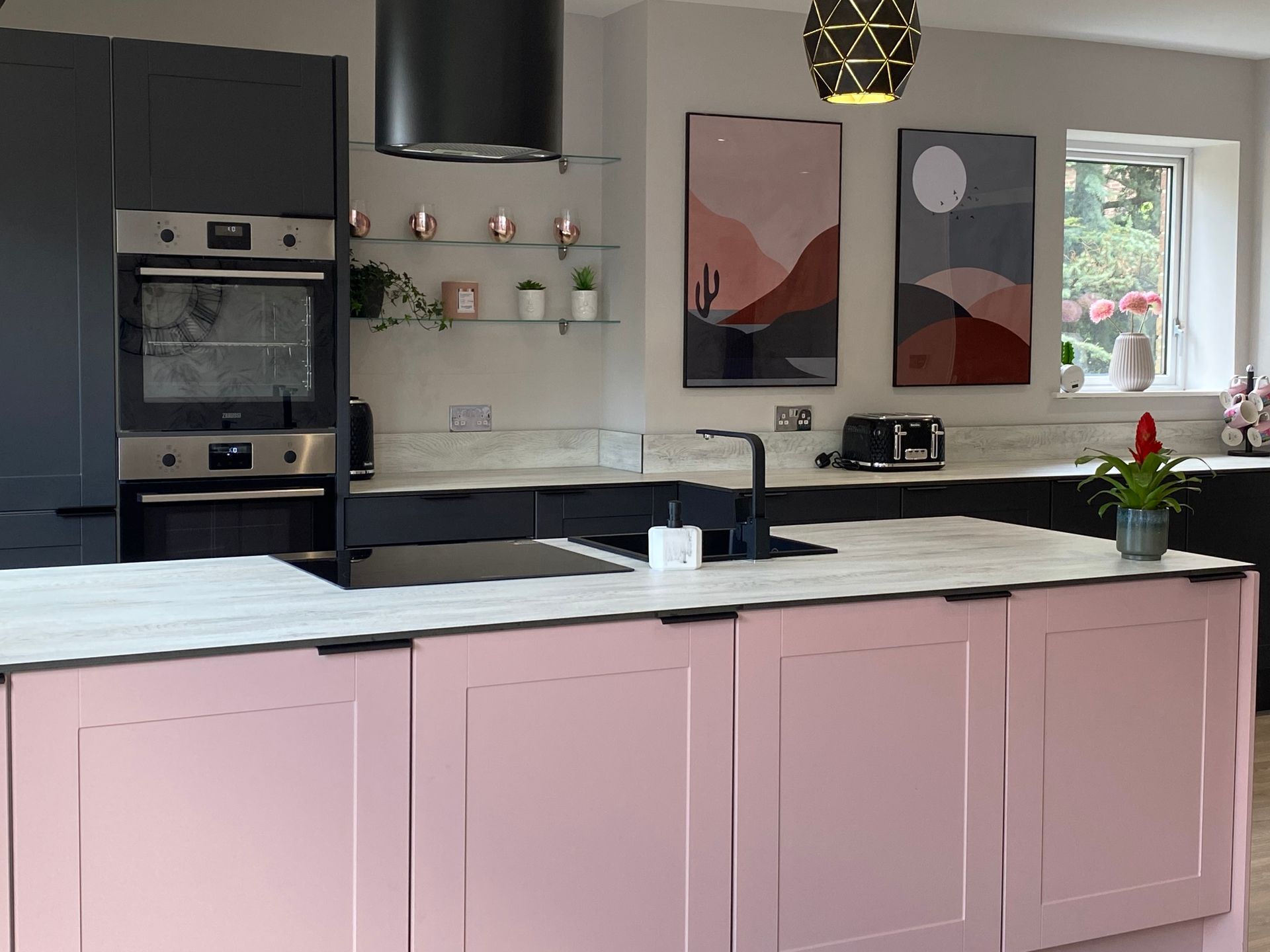 A kitchen with pink cabinets and black appliances and a large island.