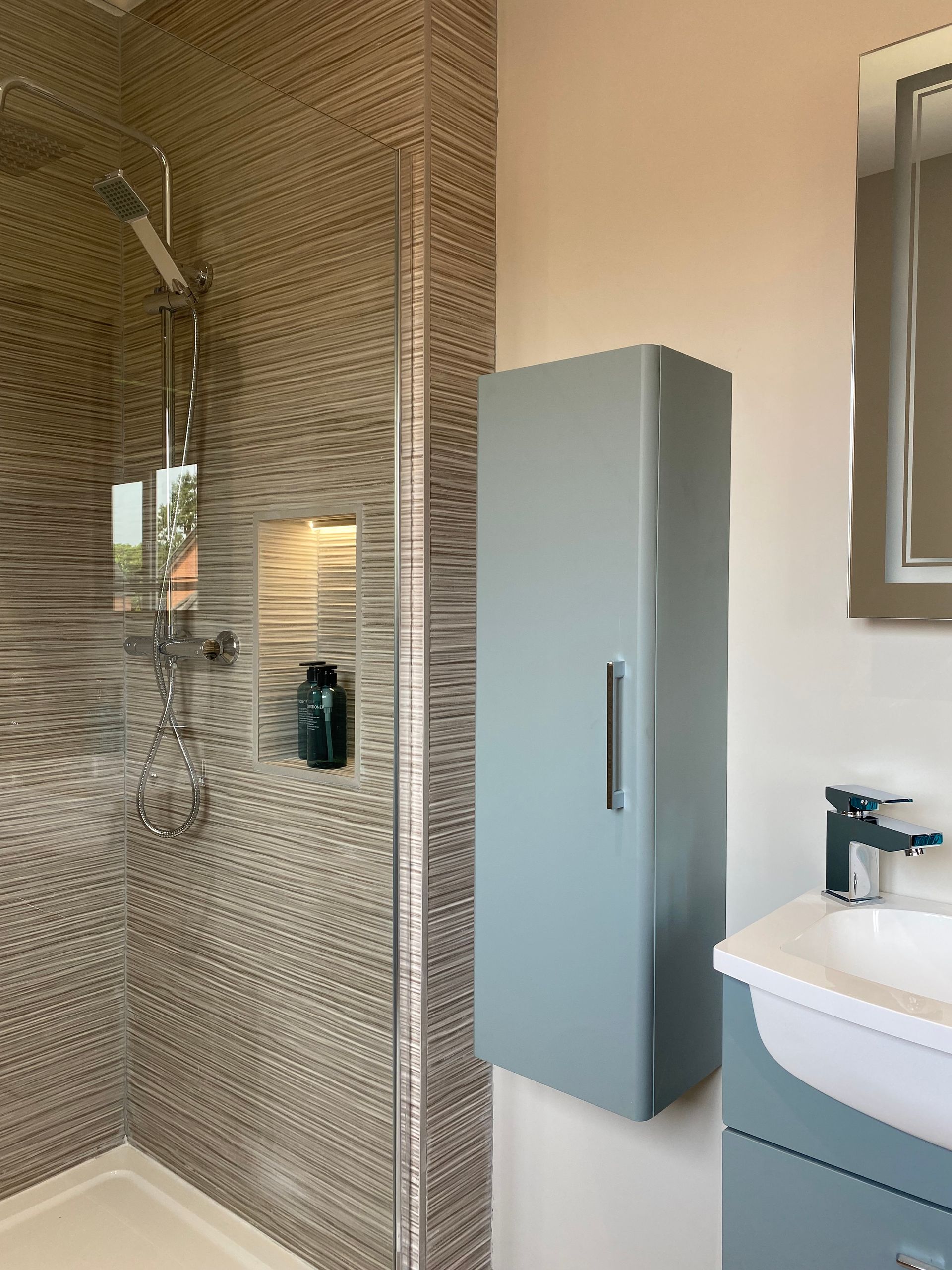 A bathroom with a walk in shower , sink and mirror.