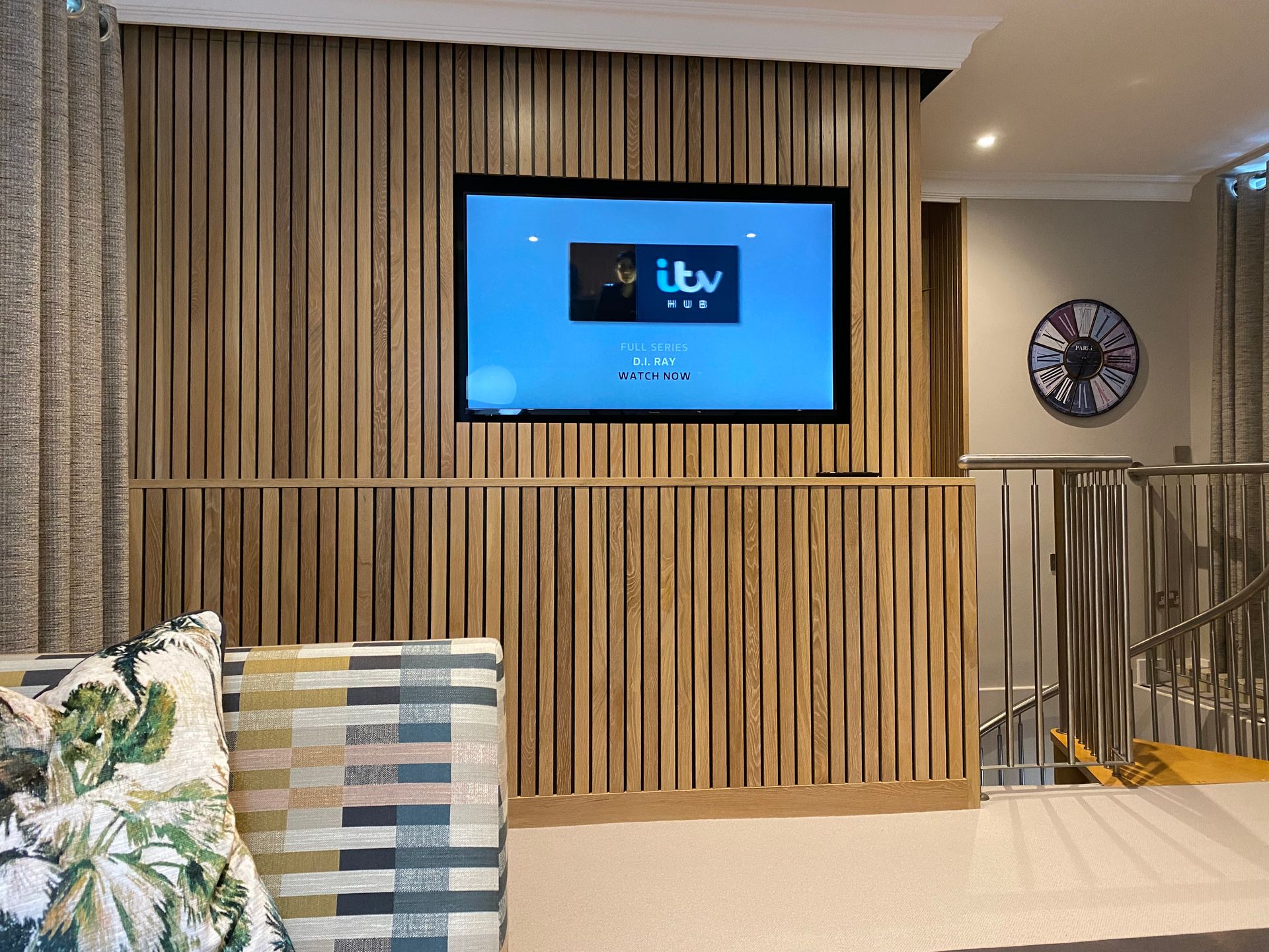 A flat screen tv is mounted on a wooden wall in a living room.