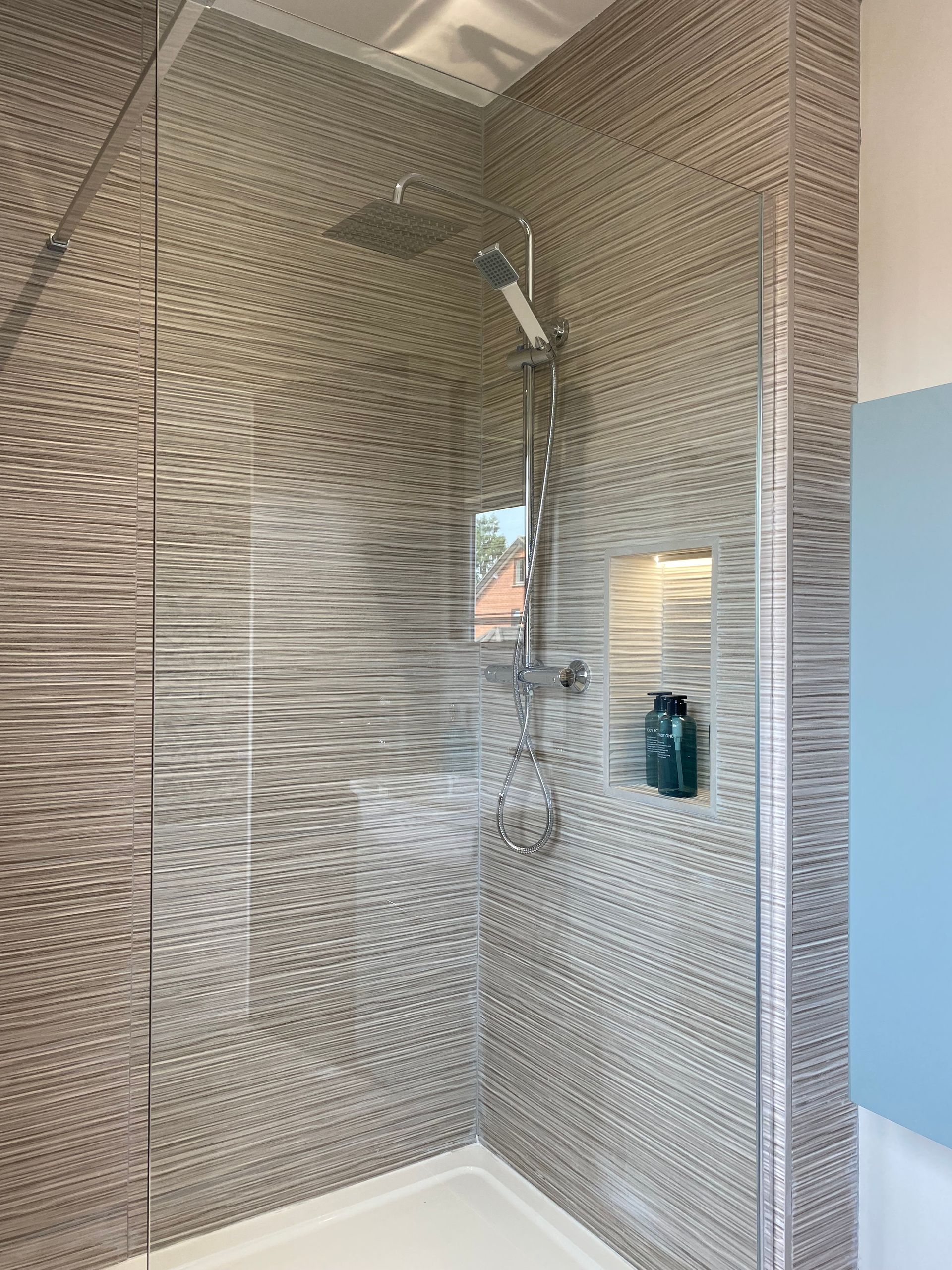 A walk in shower with a glass door and a shower head.