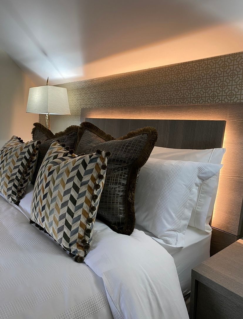 A bed with pillows and a lamp on it in a bedroom.