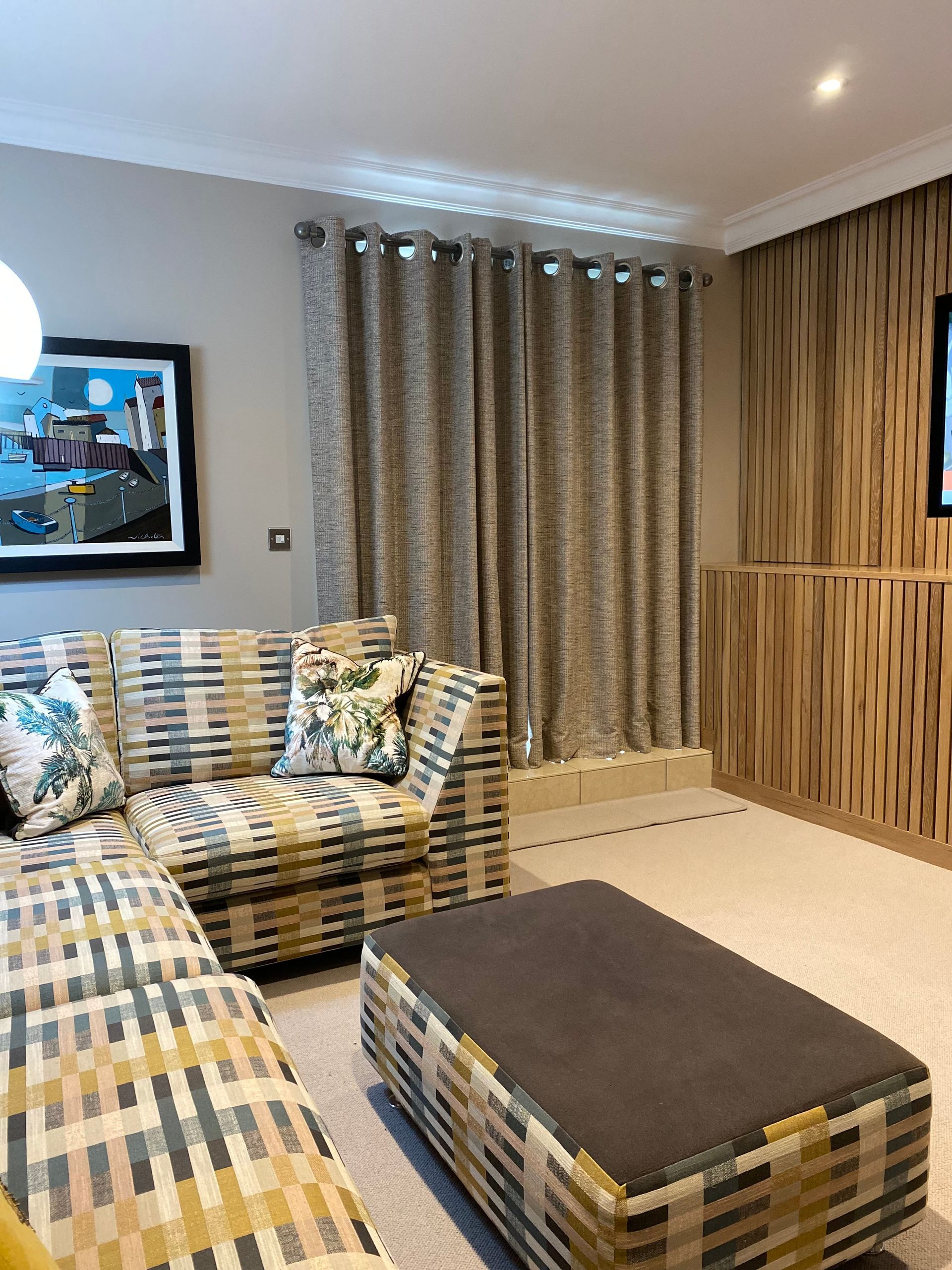 A living room with a couch , ottoman , and television.