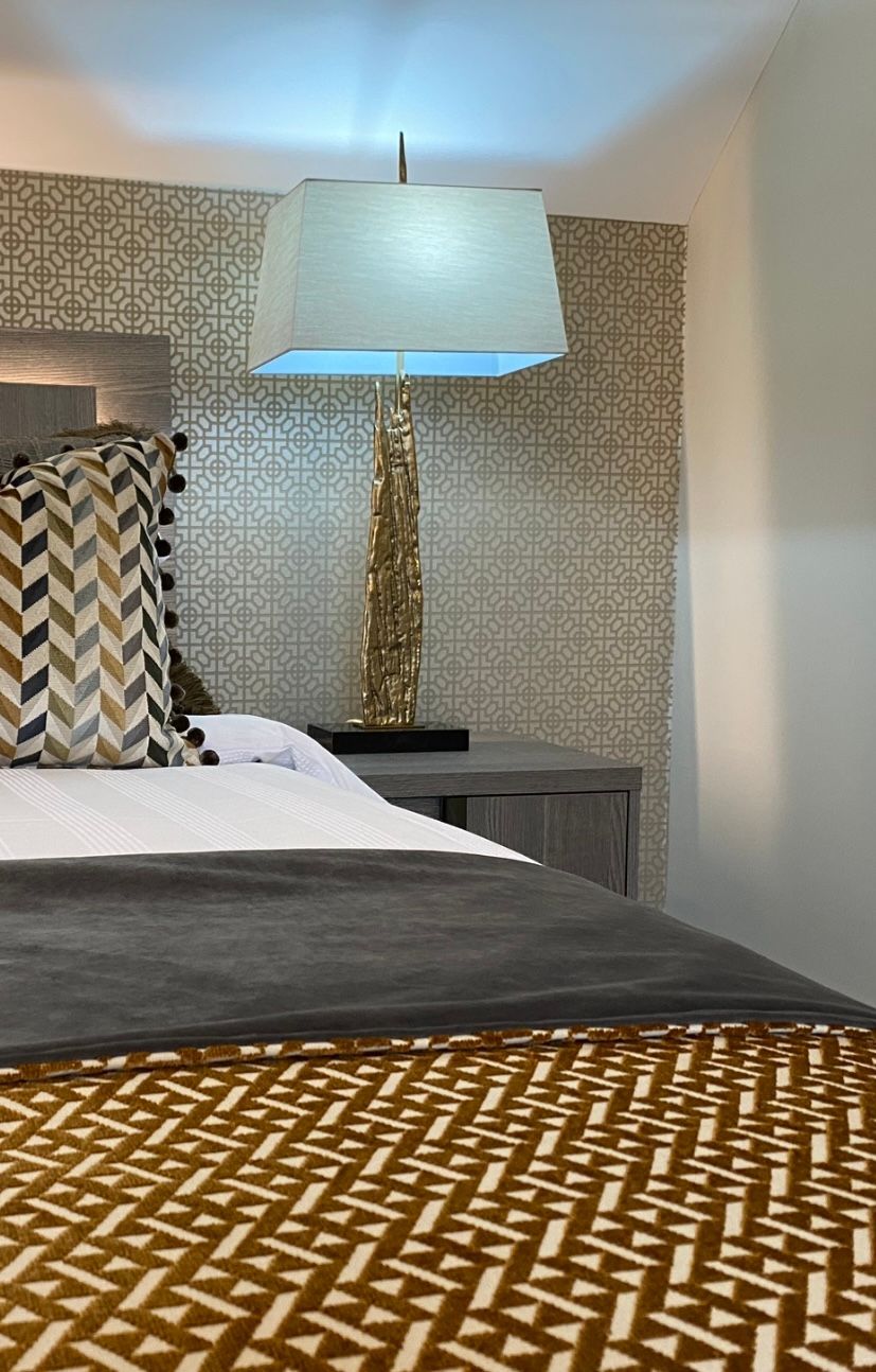 A bedroom with a bed , lamp and nightstand.