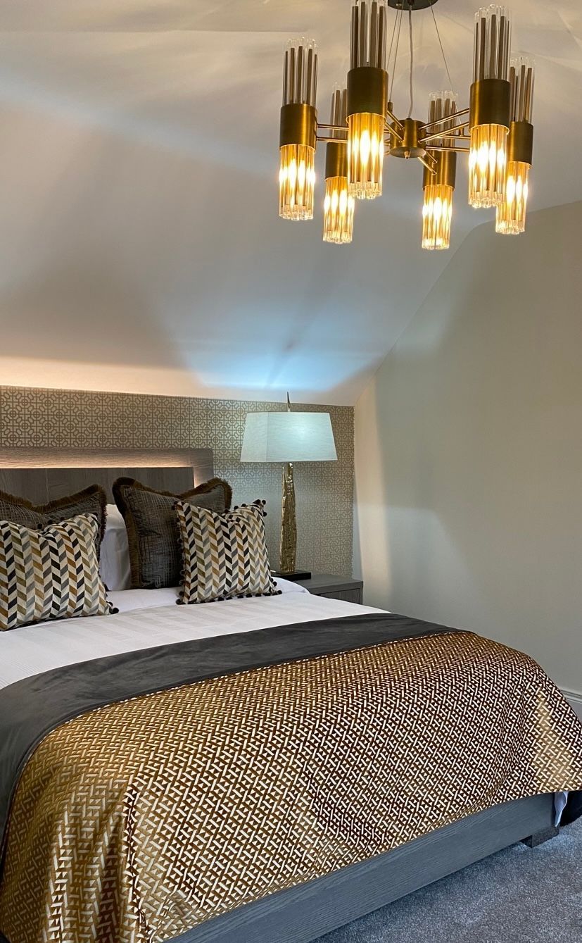 A bedroom with a bed , lamp , and chandelier.