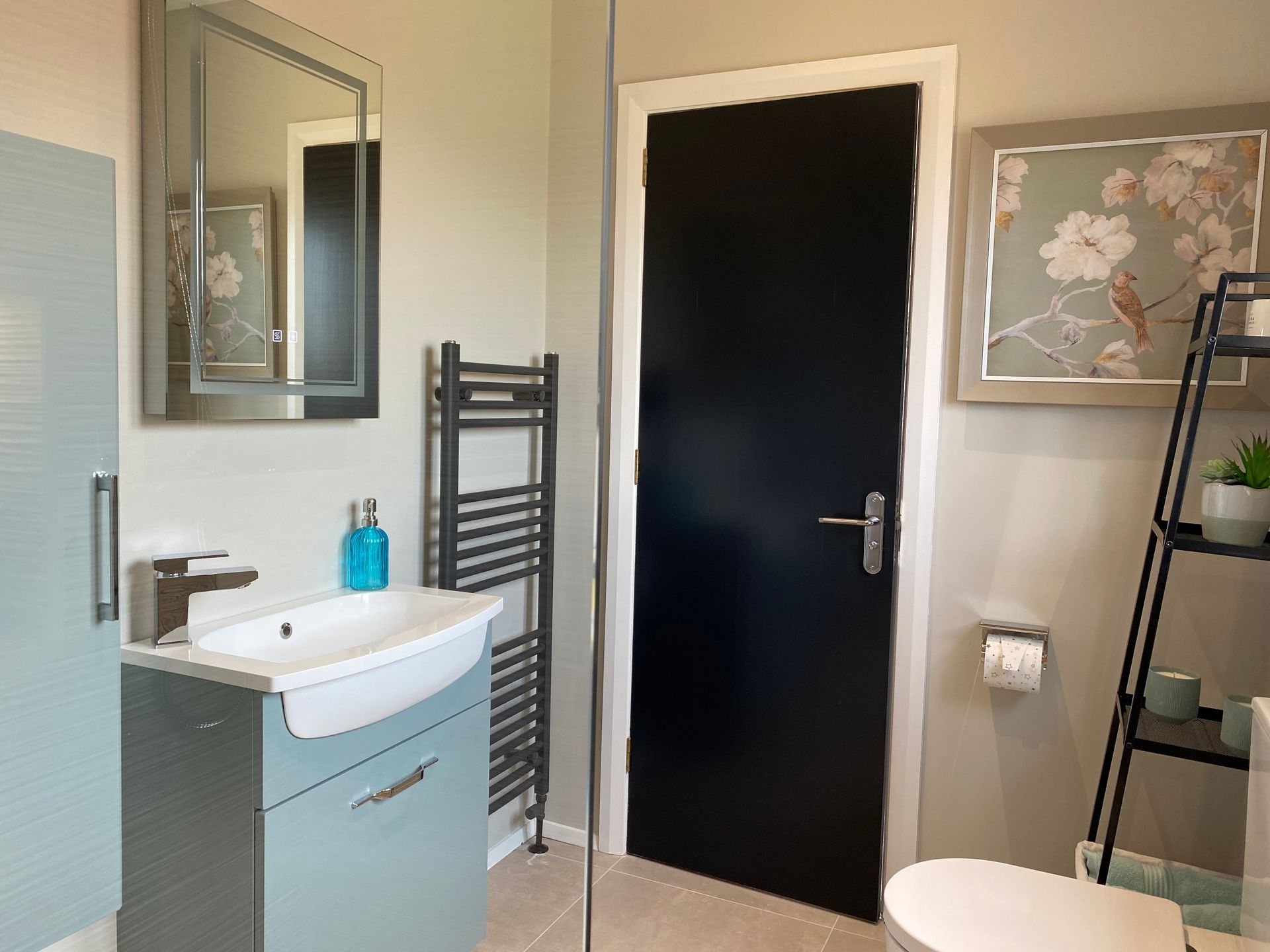 A bathroom with a sink , toilet , mirror and black door.
