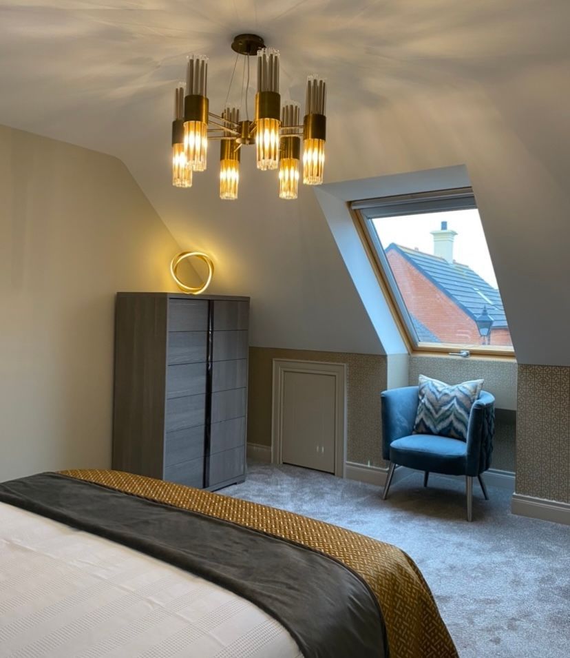 A bedroom with a bed a chair and a chandelier