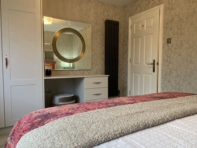 A bedroom with a bed , dresser and mirror