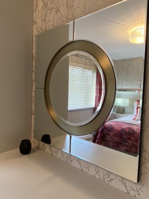 A mirror with a circle in the middle shows a bedroom