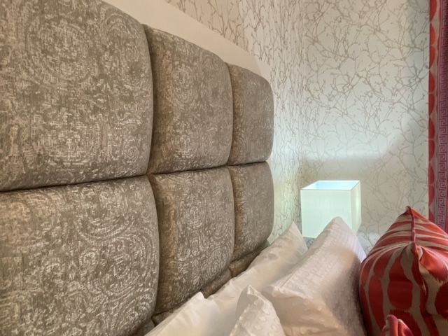 A bed with a headboard and pillows in a bedroom.