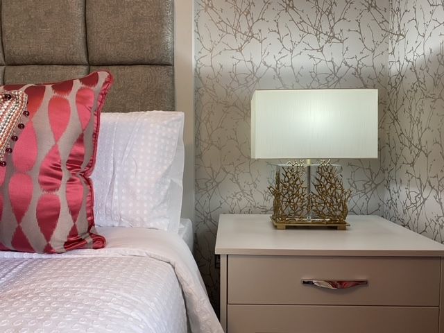 A bedroom with a bed a nightstand and a lamp