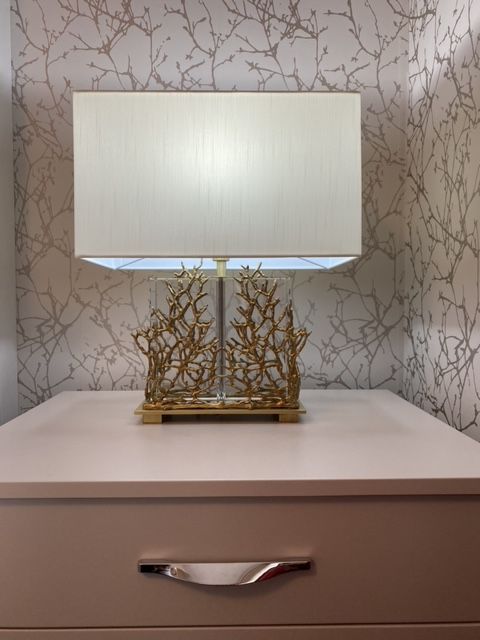 A lamp on a nightstand with a white shade