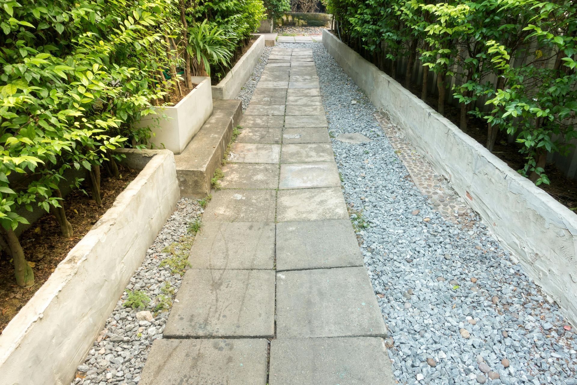 A stone walkway with gravel and trees on both sides