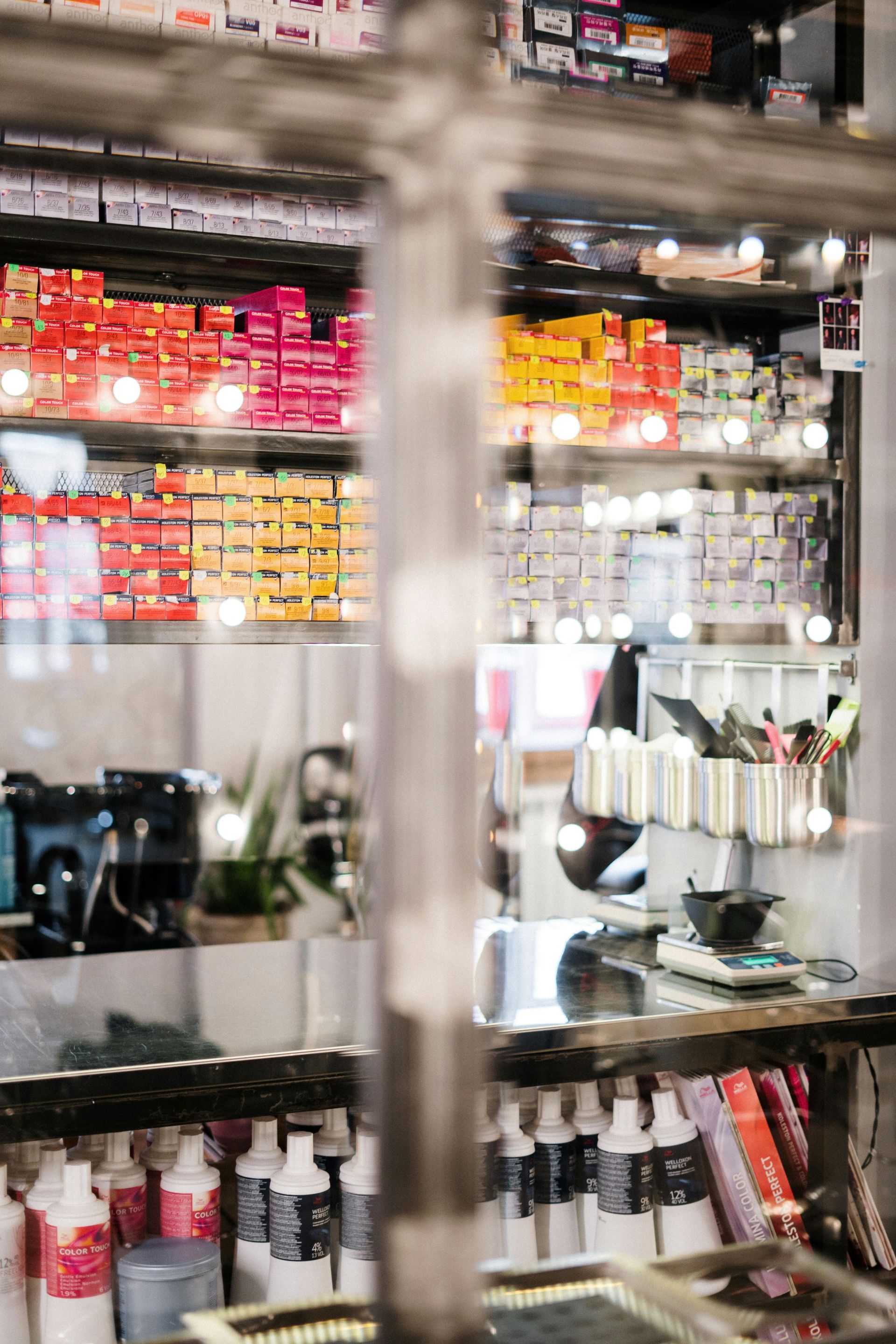 Hair dye and salon products on shelves in a mirrored display cabinet.
