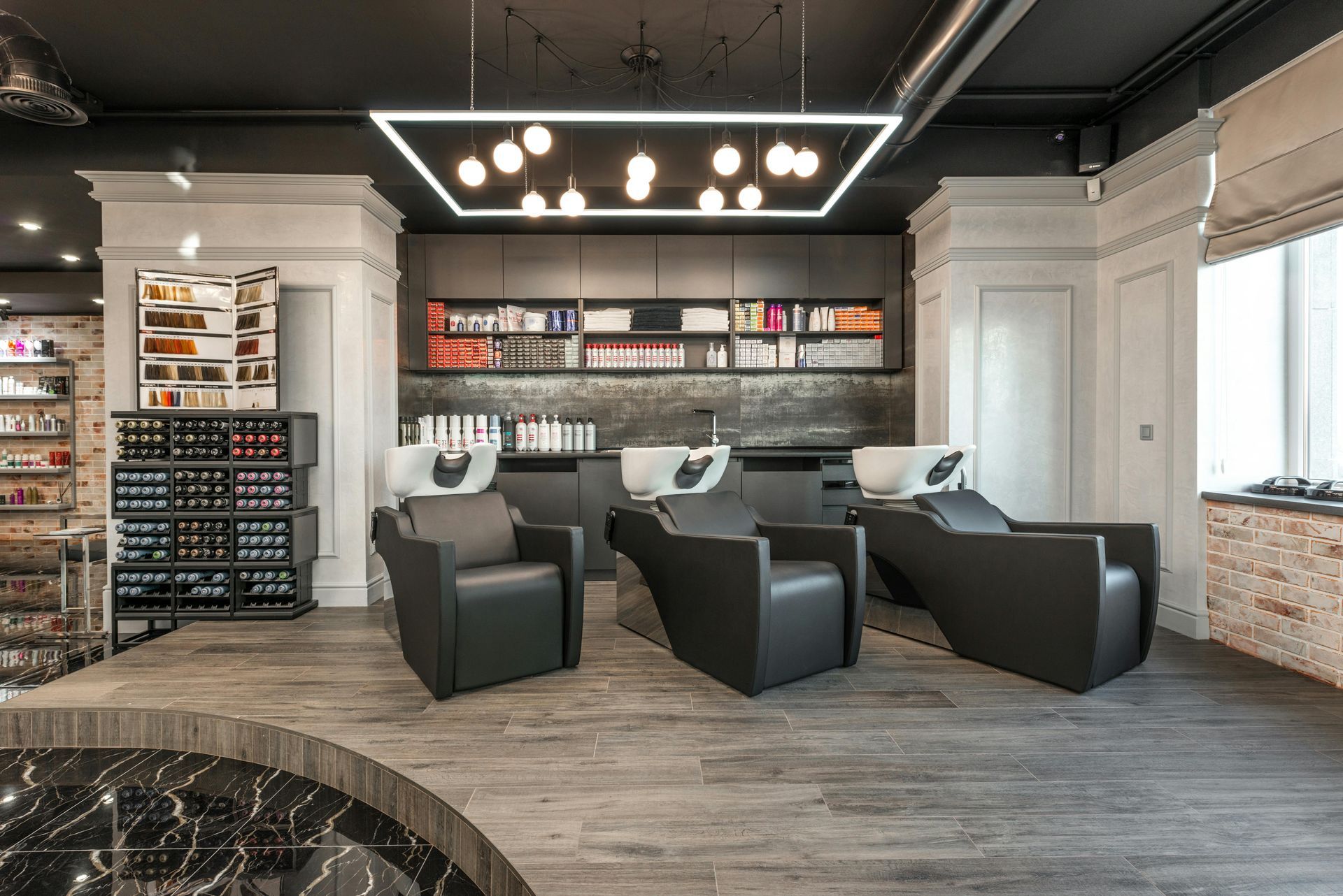 Hair salon interior with black chairs, washing stations, and shelves of products.