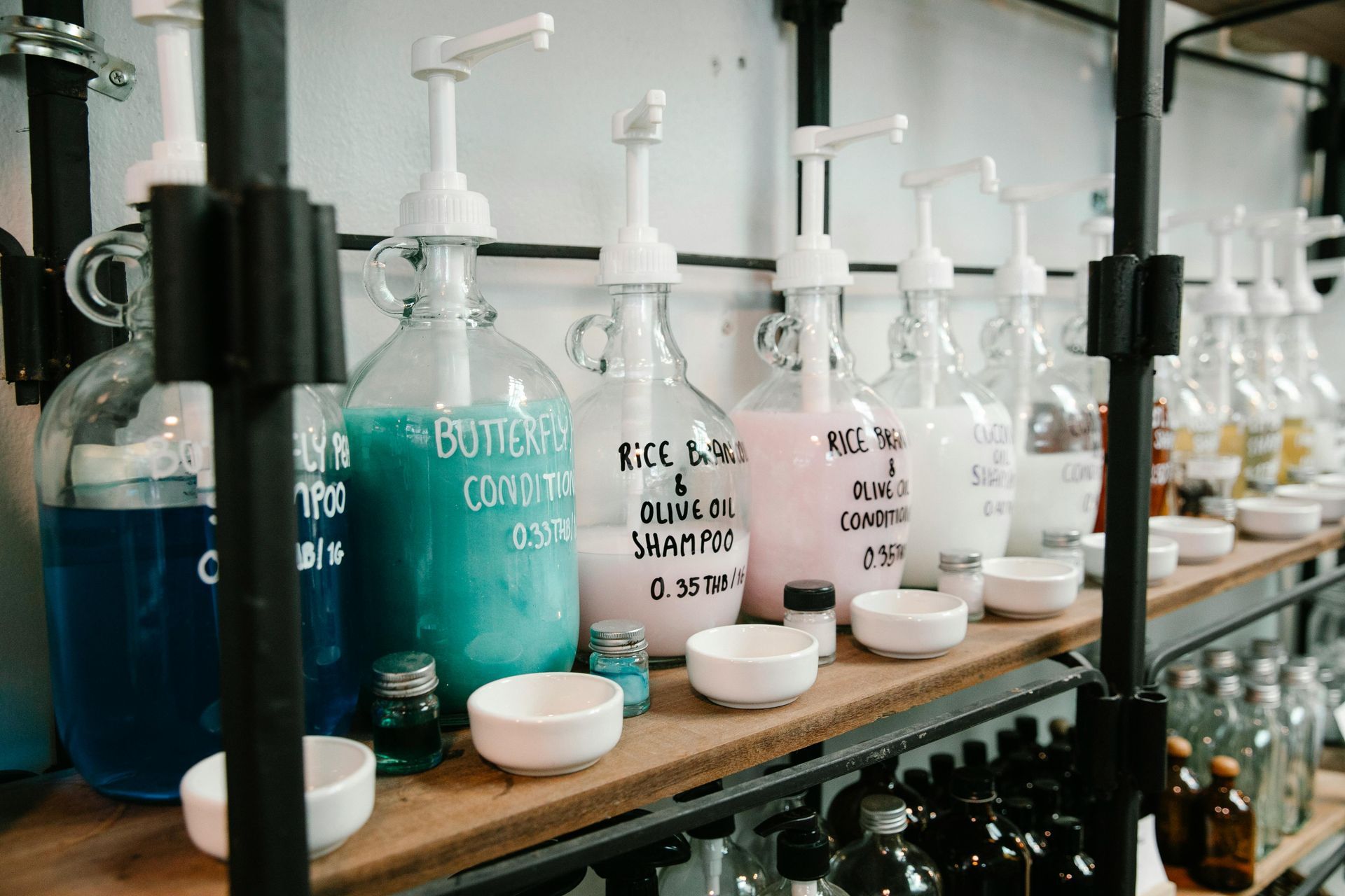 Bottles of liquid soaps and shampoos with white pump dispensers on a shelf, store.