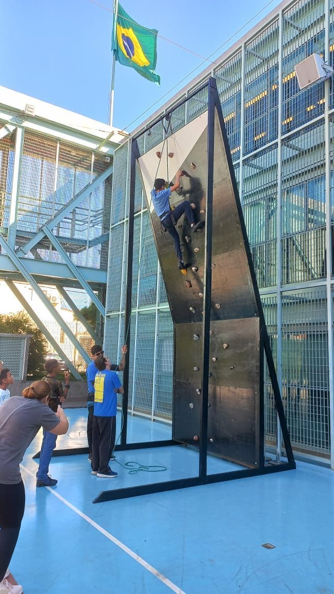 Um homem está escalando uma parede de escalada em frente a um prédio.