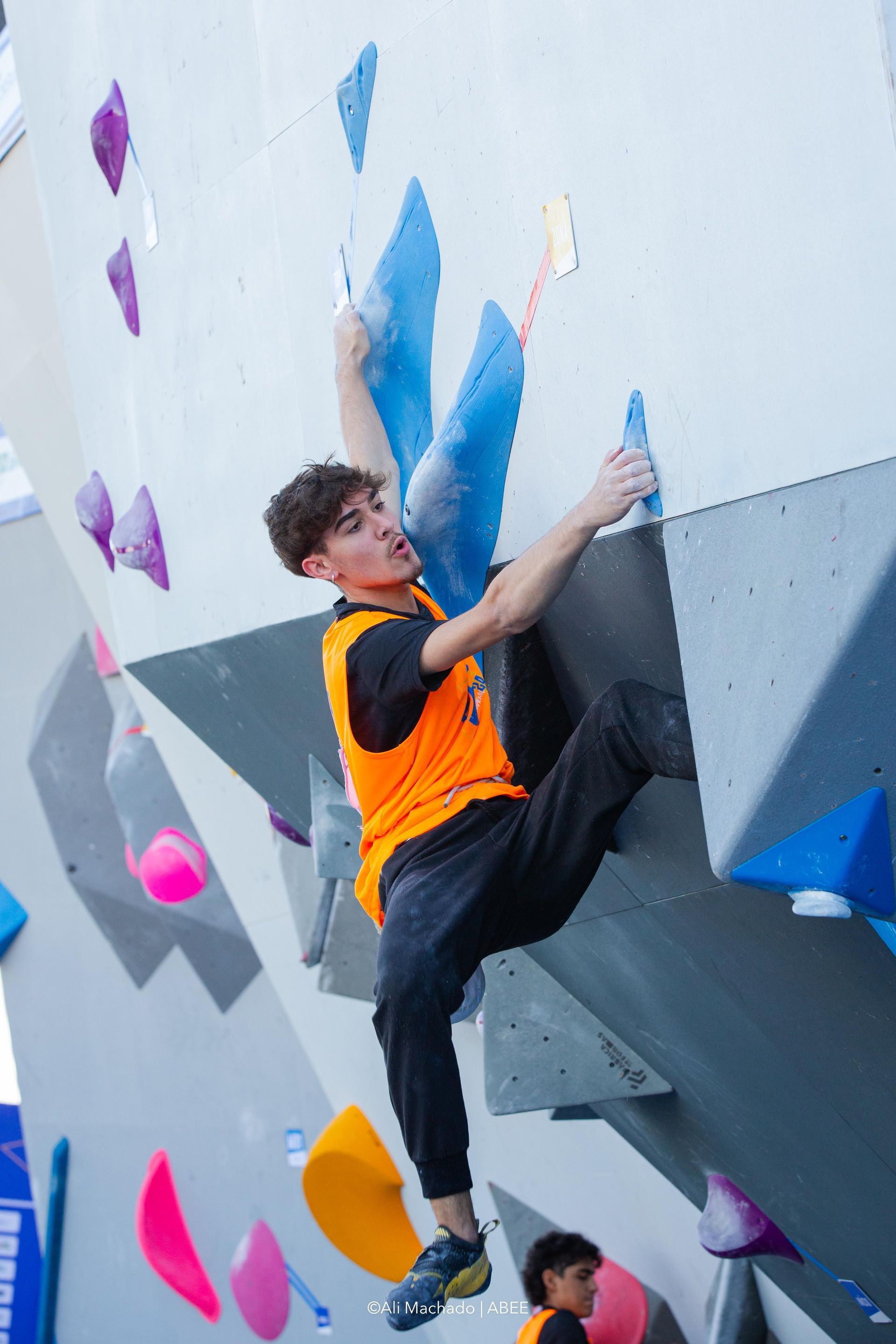 Um jovem está escalando uma parede de escalada.