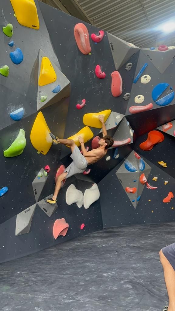 Um homem está escalando uma parede de escalada em uma academia.