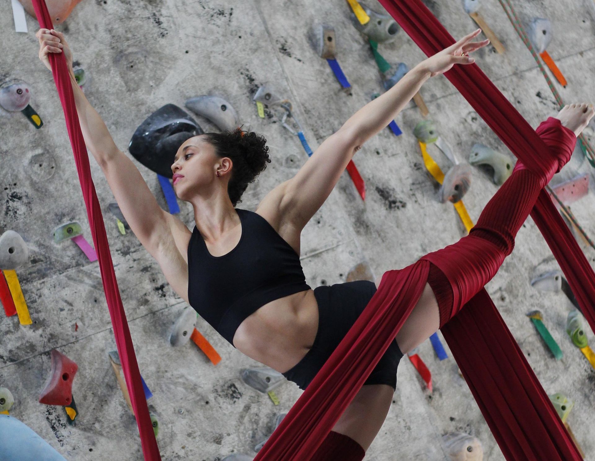 Uma mulher está fazendo acrobacias aéreas em uma parede de escalada