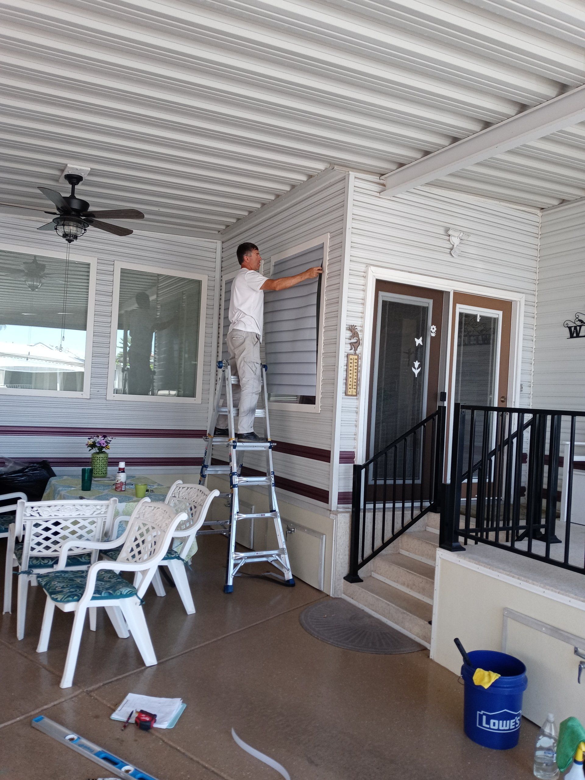 A man is standing on a ladder installing Diamond Shield for Windows.