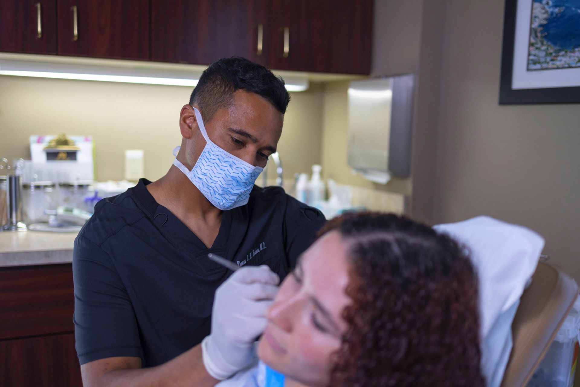Doctor in mask and gloves treating patient's skin cancer.