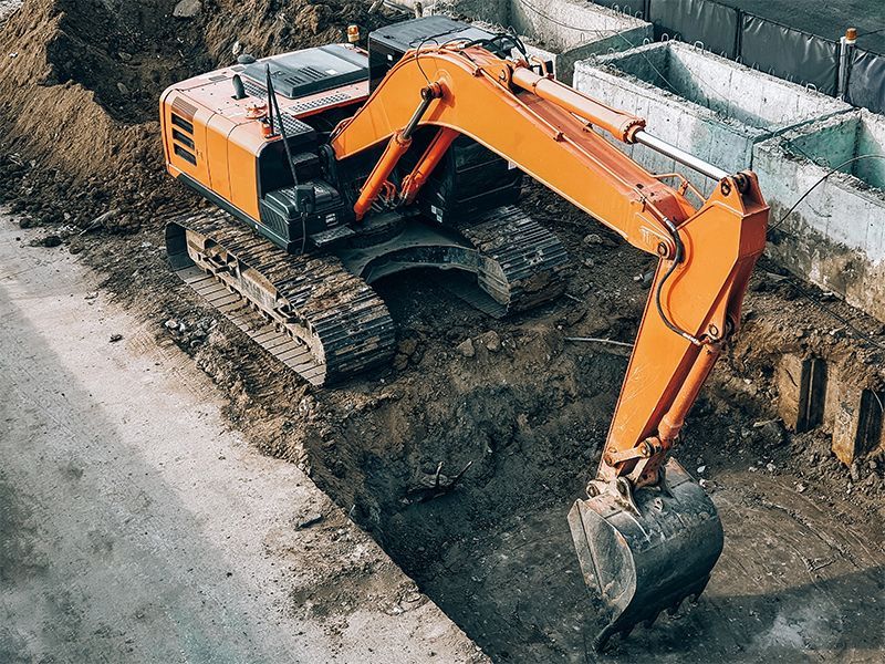Orange excavator digging a trench on a construction site.