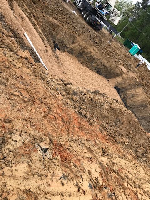 Yellow bulldozer pushing a pile of brown dirt; construction site.