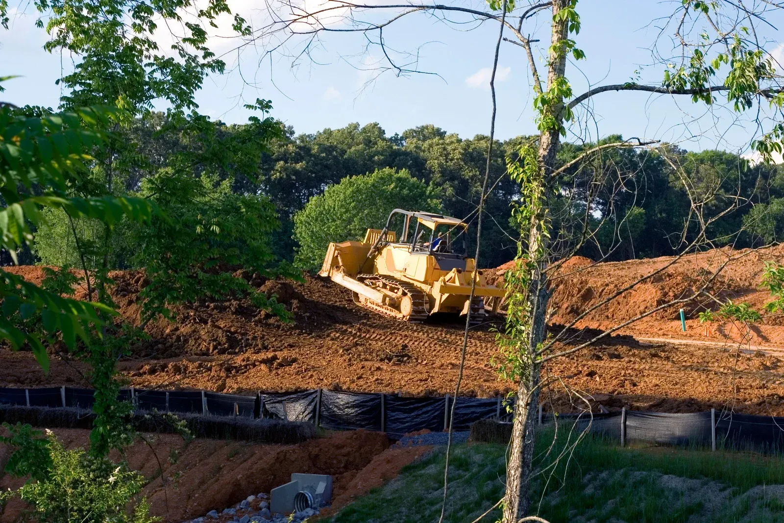 A small excavator digs into the soil within a framed area, preparing a construction site outdoors.