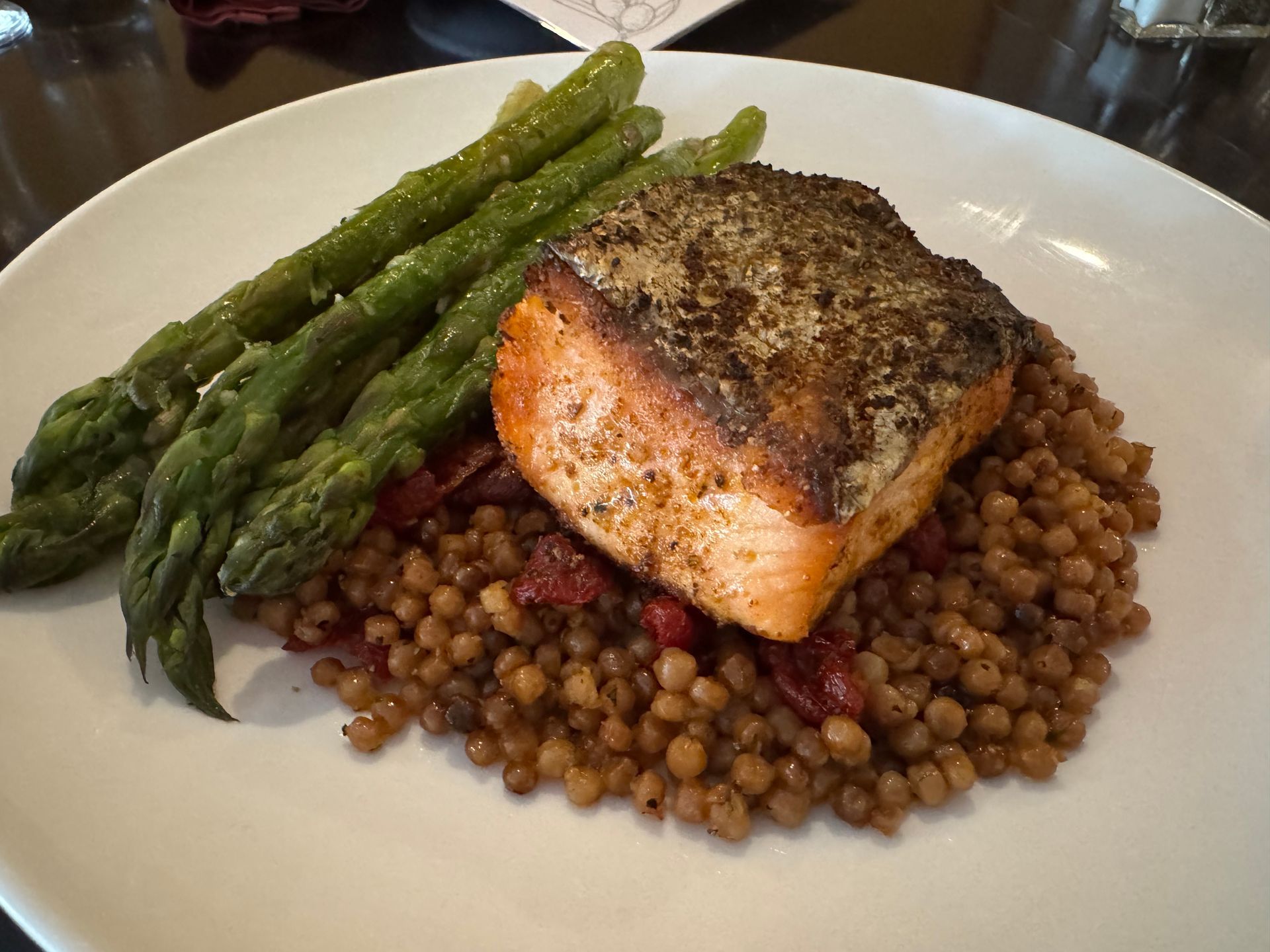 Grilled salmon with asparagus on a bed of lentils on a white plate