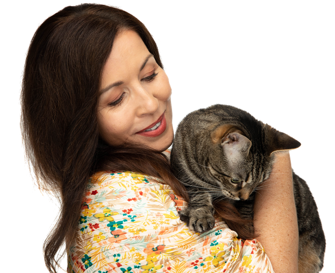 A woman is holding a cat in her arms and smiling.