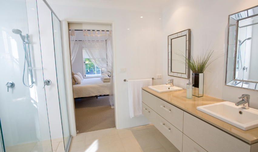 A bathroom with two sinks , a mirror and a walk in shower.