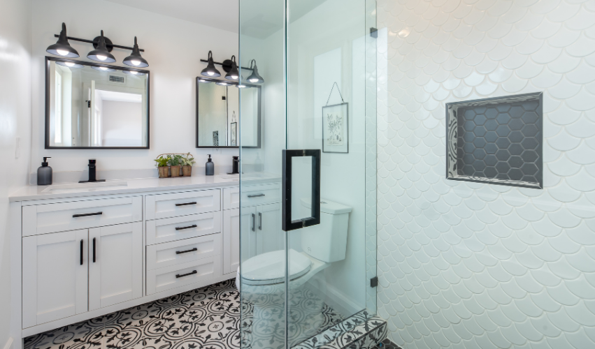 A bathroom with two sinks , a toilet , and a walk in shower.