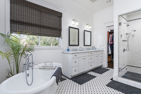 A bathroom with a tub , sinks , mirrors and a walk in shower.