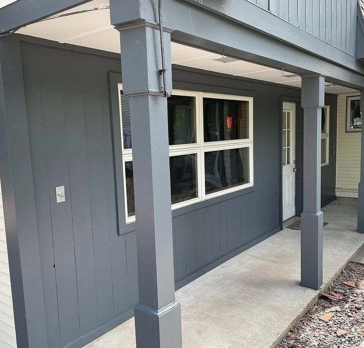 A gray house with a porch and a white door