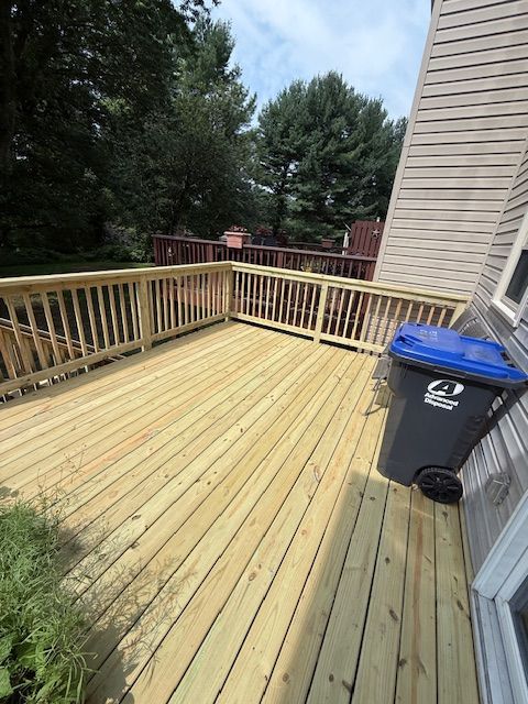 A wooden deck with a trash can on it next to a house.