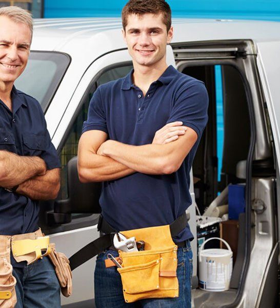 Two men standing in front of a van with their arms crossed