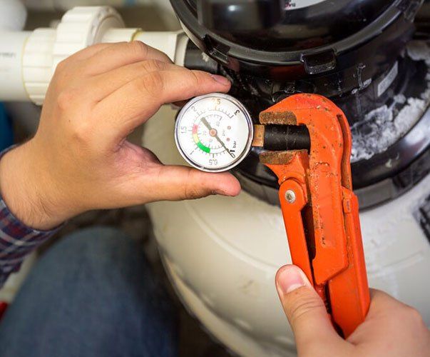 A person is holding a wrench and a pressure gauge.