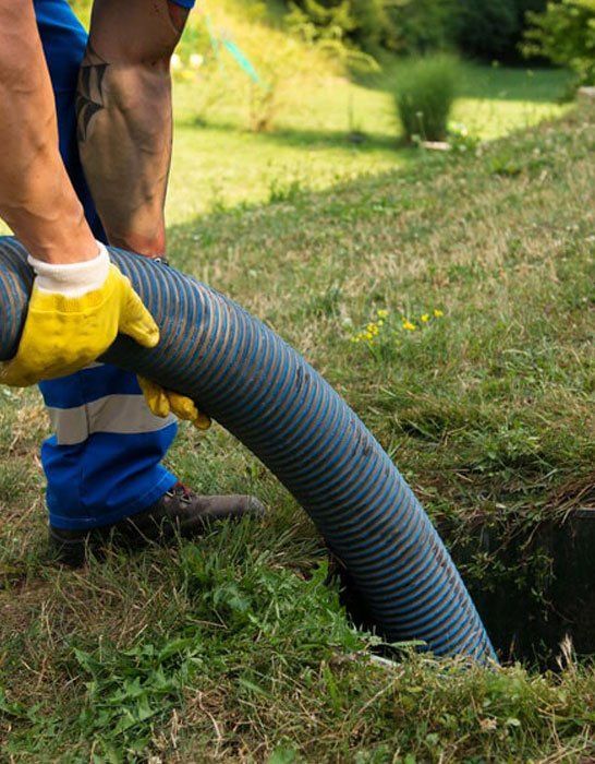 A man is pumping a hose into a hole in the ground.