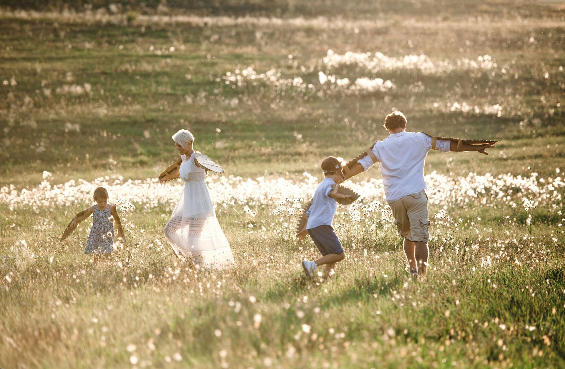 A family is running through a field of tall grass.