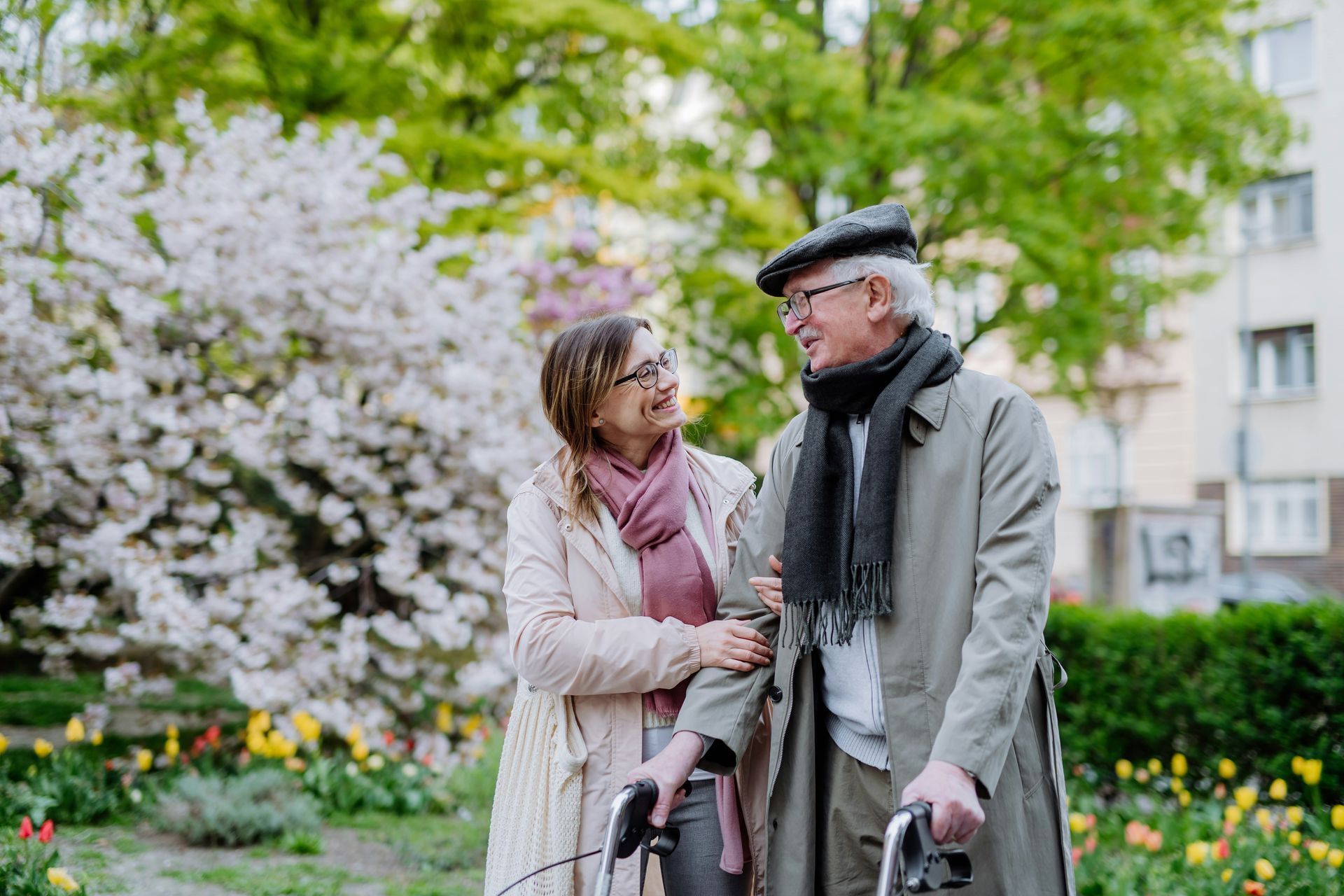 A woman is helping an elderly man with a walker in a park.